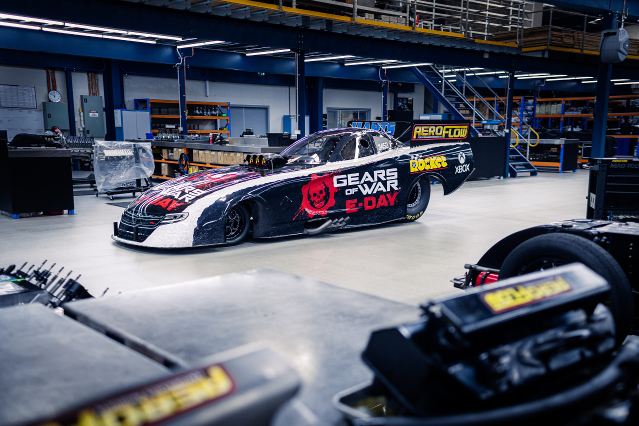 Low-angle side view of the Xbox Gears of War: E-Day Nitro Funny Car inside the Aeroflow workshop.